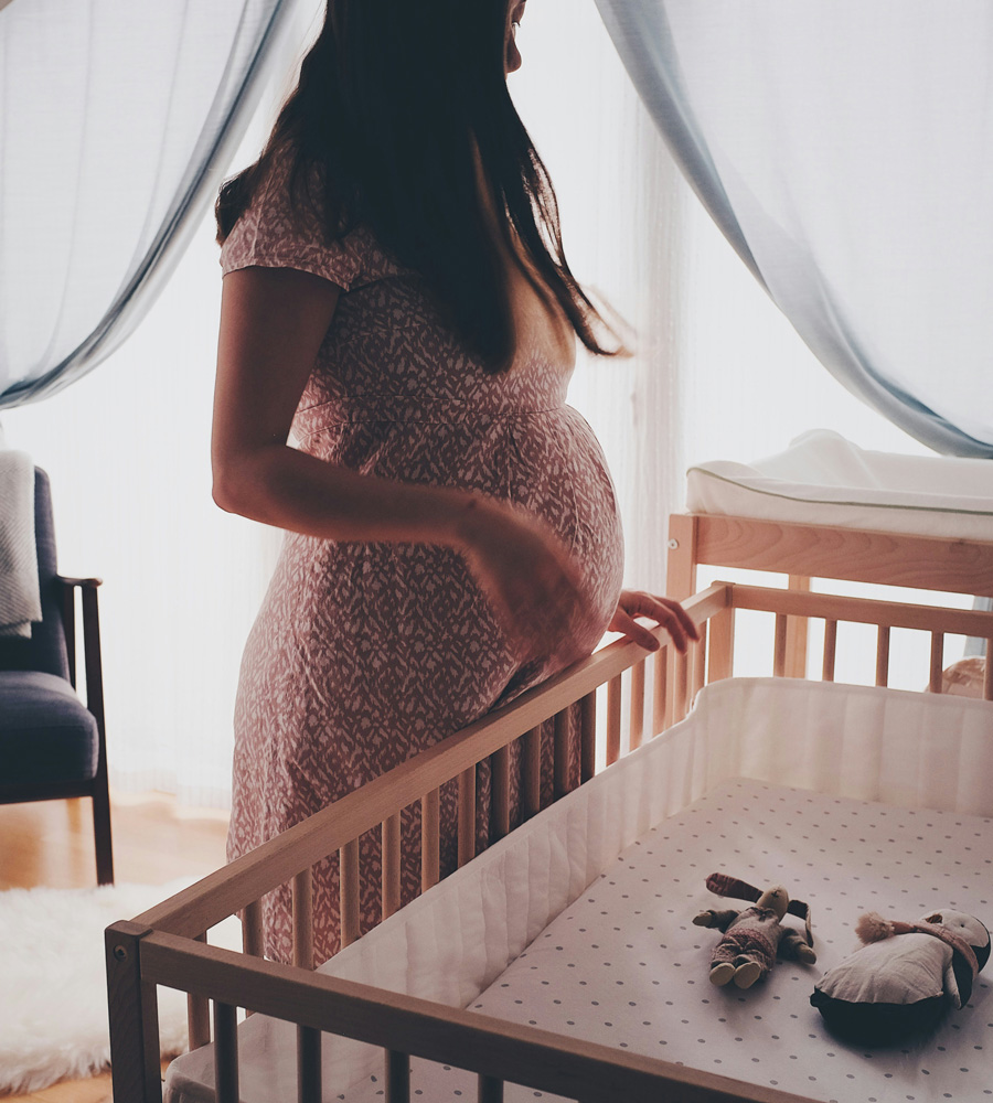 pregnant woman looking at baby's cot