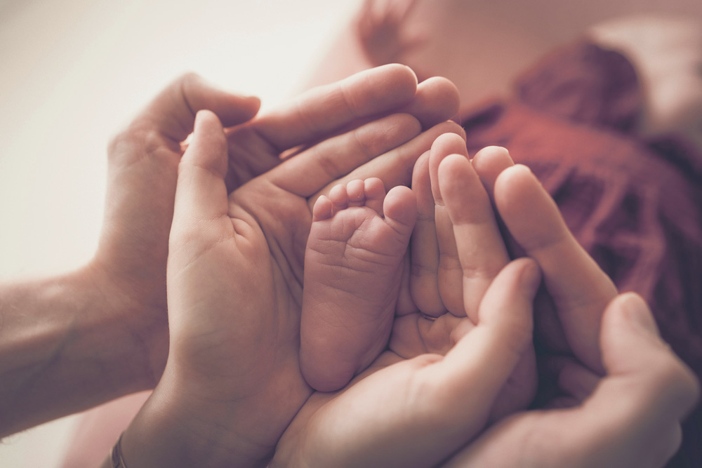 baby's foot in two adults' hands